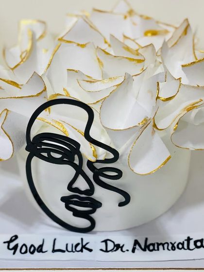 A modern and artistic cake with a line-art face design for a doctor.