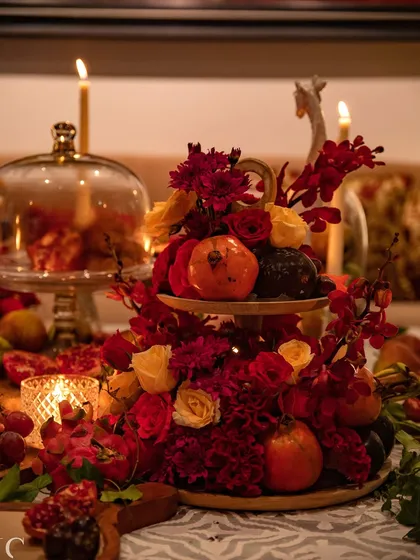 A two-tiered arrangement featuring a mix of red and yellow roses, pomegranates, and other botanicals. This piece serves as a focal point, demonstrating how I integrate edible elements directly into the floral design.