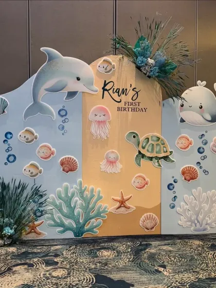 A sweet and gentle underwater theme for Rian's first birthday. This custom backdrop features adorable illustrations of a dolphin, whale, turtle, and other friendly sea creatures.