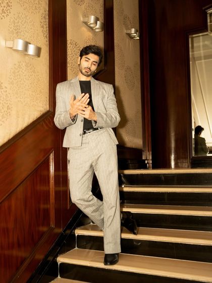 A full-length environmental portrait of actor Ishwak Singh for a GQ feature. The staircase location adds a classic, masculine feel to the shot.