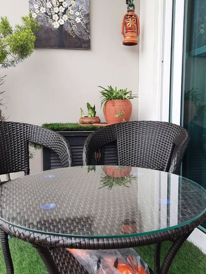 A classic outdoor furniture set with two wicker chairs and a glass top table. This is a simple and functional setup for any balcony.