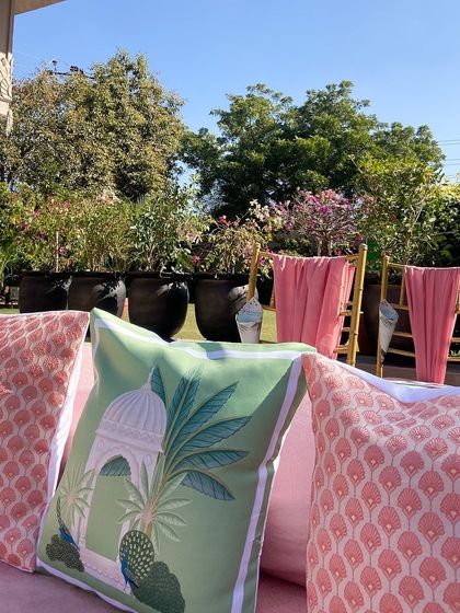 Custom-printed cushions featuring motifs inspired by the venue's architecture, placed on a pink lounge sofa. This is how we tie the decor into the natural beauty of the space.