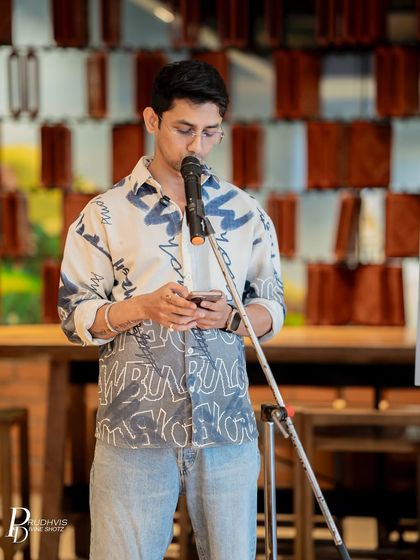 A poet reads intently from his phone, dressed in a creative, artistic shirt that reflects his personality. Our community is a melting pot of unique individuals.