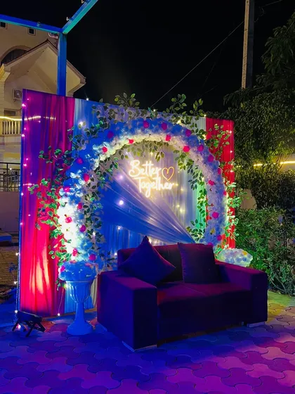 An outdoor 'Better Together' decoration for a couple's celebration. This setup includes a floral arch, a neon sign, and dramatic lighting.