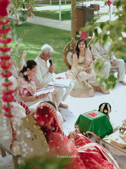 A candid moment from an outdoor wedding ceremony. The families are involved, and the atmosphere is full of love and happiness.
