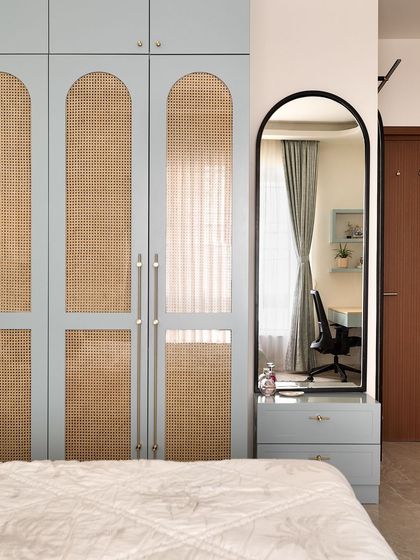 Arches can soften a space and add a sense of fluidity. Here, I used them on a powder blue and cane wardrobe, creating a design that is both elegant and timeless. The arched mirror next to it continues the theme.