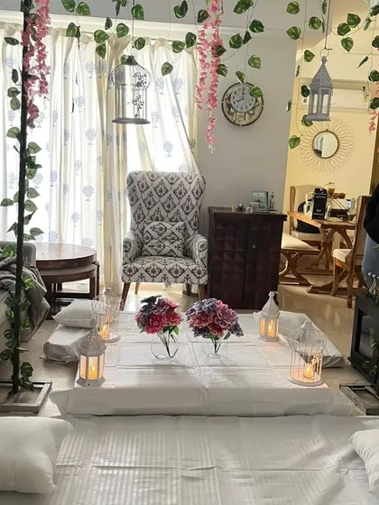 An elegant low-seating dinner setup at home, decorated with artificial vines, flowers, and lanterns for a romantic evening.