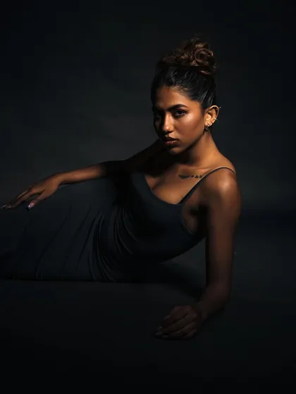 A dramatic, floor-based pose. The single light source creates a spotlight effect, highlighting the model's form and expression.
