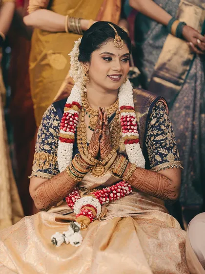 The bride in a moment of prayer during her ceremony. Her hands, adorned with henna, are folded gracefully.