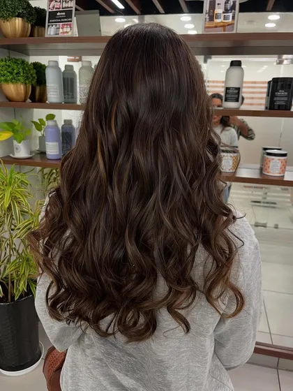 This client's long hair looks stunning with these whiskey brown balayage tones and loose curls.