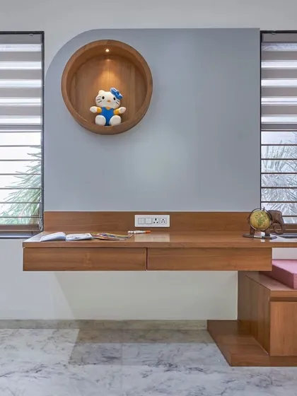 A clever use of space in a child's room. This floating wooden study desk is paired with a circular wall niche, creating a perfect, well-lit spot for homework and creativity.