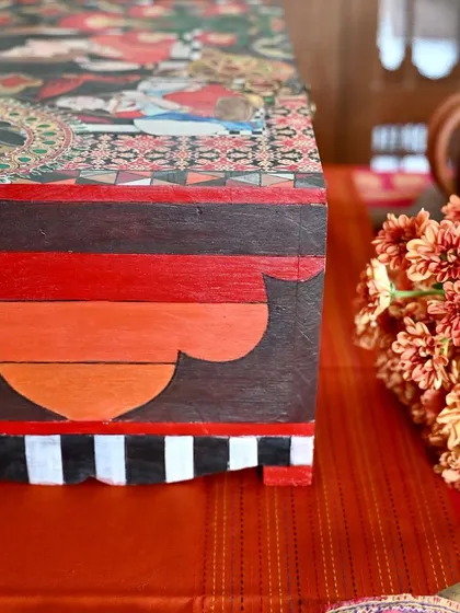 A side view highlighting the hand-painted base and striped border. Every surface of the box is considered, making it a complete work of art from every angle.