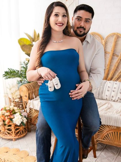 A proud and happy portrait of the parents-to-be. Holding a pair of baby shoes, they look at the camera, ready and excited for their new roles as mom and dad.