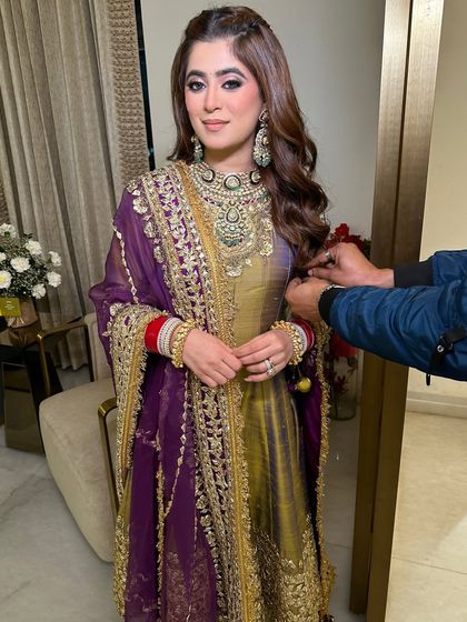 A behind-the-scenes moment, capturing the final touches to her outfit. Her makeup remains flawless, showcasing a look that is both bold and elegant.