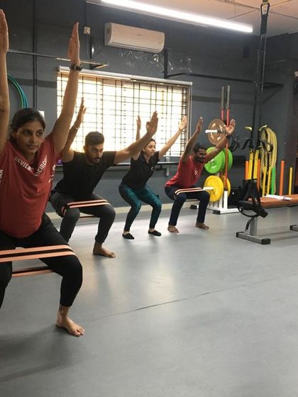 A group of students performs resistance band squats, a great example of the functional strength exercises we cover in our courses.