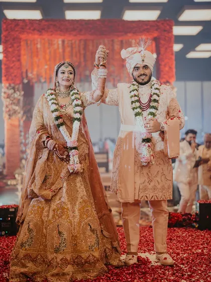 The couple, now officially united, raises their hands in celebration on a carpet of red rose petals. We ensure every moment, from the solemn vows to the joyous exit, is picture-perfect.
