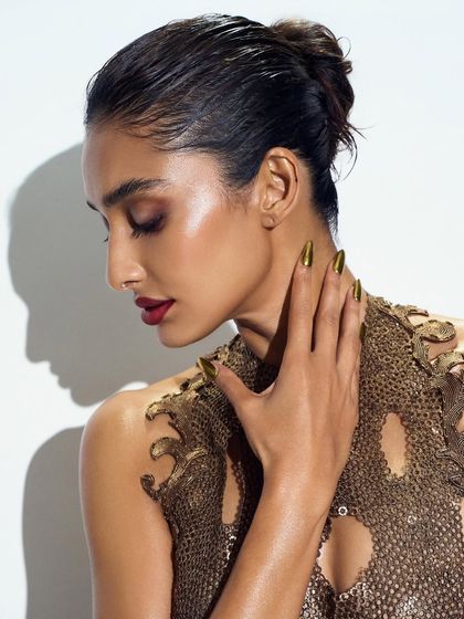 The elegance of gold chrome nails. This side profile shows how the nail shape and color can complement the model's features and the overall mood of the shoot.