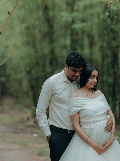 A sweet and gentle pose, with the partner embracing the mom-to-be from behind. The white off-shoulder gown adds to the romantic and pure feel of the moment.