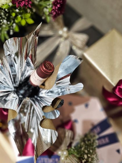 I love finding creative ways to wrap items, like this bottle of wine. Here, I used a dramatic silver and gold foil wrap that adds a celebratory and glamorous feel to the hamper.