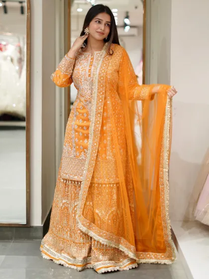 Bright, bold, and beautiful, this orange sharara set is perfect for a Sangeet or festive celebration. The kurta is heavily embroidered, and the flowing sharara pants are made for dancing the night away.