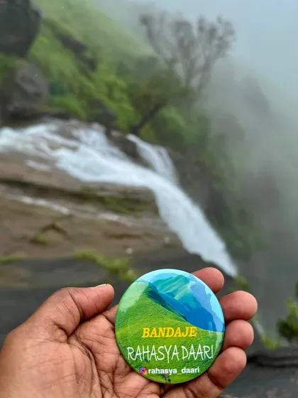 A creative shot holding our custom "Bandaje" badge with the beautiful Bandaje falls in the soft-focused background.