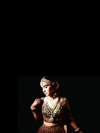 A minimalist and artistic portrait focusing on the bride's face and jewelry against a stark black background.