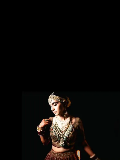 A minimalist and artistic portrait focusing on the bride's face and jewelry against a stark black background.