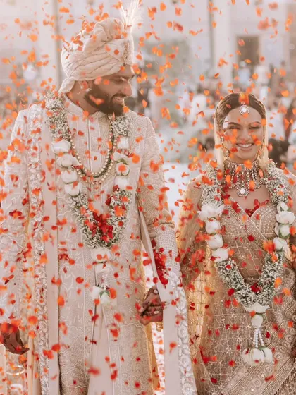 A shower of orange petals rains down on the newly married couple as they walk away from the mandap, hand in hand. This explosion of color and happiness is the perfect end to a beautiful ceremony.