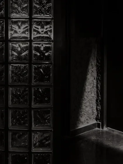 An enigmatic realm of lights and shadows. The glass block wall is a signature element, casting distorted reflections and adding to the mysterious atmosphere of the space.