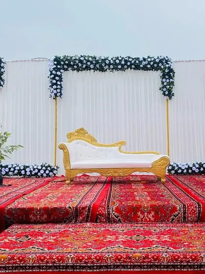 The same Sangeet stage seen during the day, showing the clean lines and the contrast of the white and black flowers.