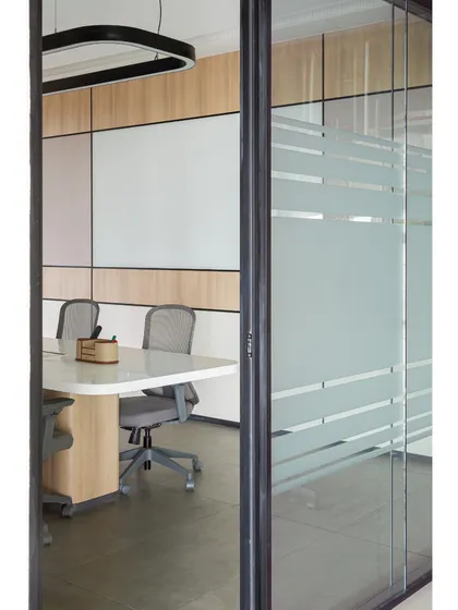 A view into the conference room from the outside, showing the frosted glass that provides privacy while still allowing light to pass through. The design ensures that even enclosed spaces feel connected to the rest of the office.