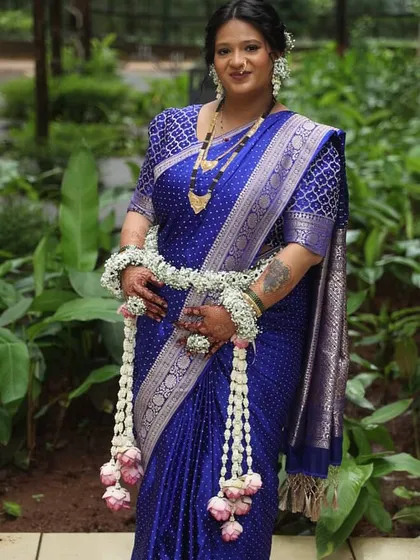 A beautiful mom-to-be in a royal blue saree, complemented by a fresh floral set of white flowers and pink lotus buds. The contrast of colors is absolutely stunning.