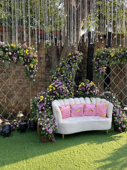 A chic and comfortable Mehendi seating area. We used a mix of yellow and lavender florals against a garden backdrop to create this inviting and stylish photo spot.