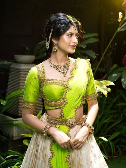 Wrapped in elegance, this half saree features a light gold tissue lehenga paired with a vibrant lime green princess katori blouse. The entire ensemble, including the dupatta, is finished with intricate handwork for a look of traditional grace.
