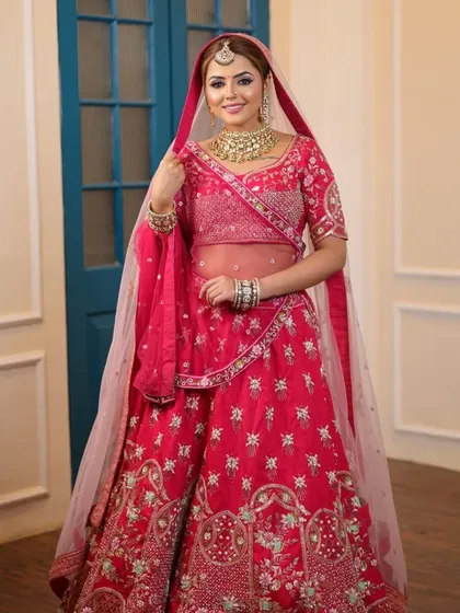A model posing in a pink lehenga with a sheer dupatta, her Kundan jewellery adding a touch of traditional elegance.