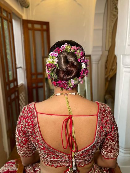 A full, rounded bridal bun completely encircled with fresh, multicolored flowers. This style is a celebration in itself, perfect for a bride who wants a bold and traditional floral hairstyle for her big day.