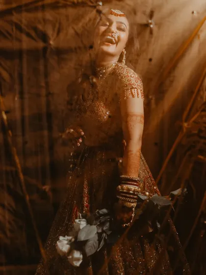 A candid shot of the bride's infectious laughter, captured through a textured foreground for an artistic effect.