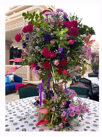 A tall, tree-like centerpiece of purple, pink, and red flowers, designed to bring height and drama to the tables.