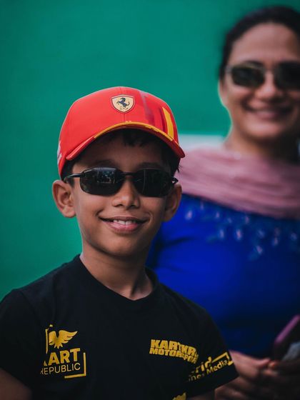 A young driver smiling with his mother in the background.