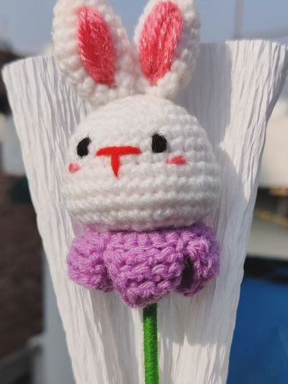 A close-up of the crochet bunny's face on the flower bouquet.
