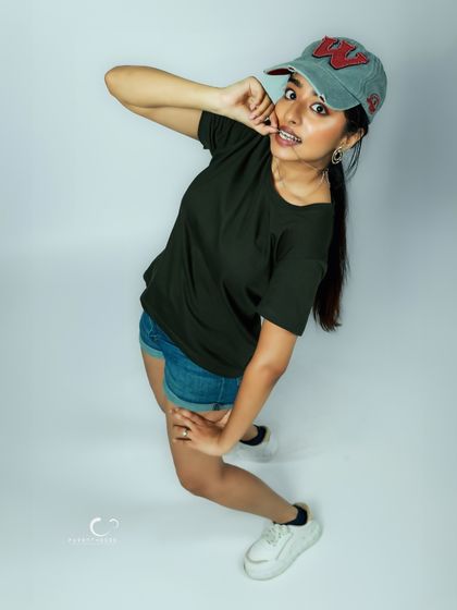 A fun, high-angle shot that gives a different perspective. The casual styling with the cap and shorts creates a relaxed and youthful vibe.
