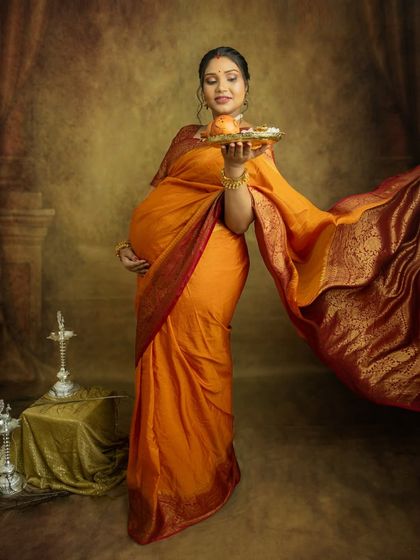 The flowing fabric of the saree adds a touch of drama and elegance to this full-length portrait. It’s a powerful image of a mother-to-be in all her glory.