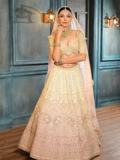 A full-length portrait of the bride in her stunning ivory lehenga. The soft makeup and elegant silhouette create a look of pure sophistication.