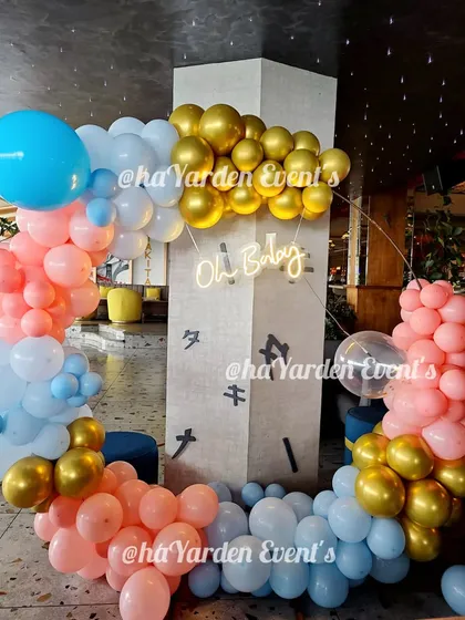 A circular balloon frame in pink, blue, and gold for an 'Oh Baby' shower. The neon sign adds a modern touch to this beautiful setup.