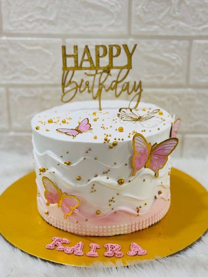 A close-up of a beautiful pink and white ombre butterfly cake, showing the delicate details and gold sprinkles.