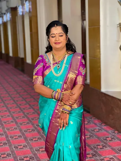 Swathi looking serene and beautiful for her reception. The turquoise and magenta saree is a vibrant choice, and her makeup is kept soft and elegant to complement it.