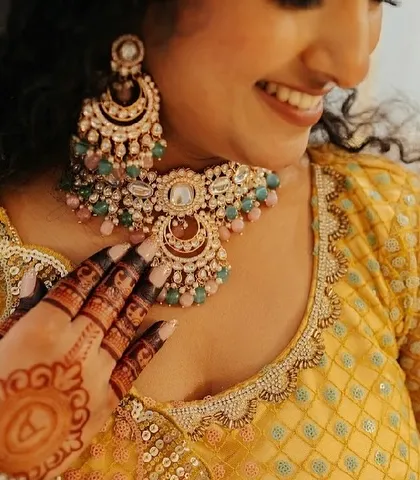 A happy client at her engagement, smiling as she shows off her mehendi. The dark stain on her fingers and the initial on her palm are beautifully visible.