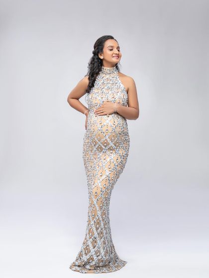 A serene moment in the sparkling sequin gown. The simple white background keeps the focus on the intricate details of the dress and her beautiful smile.