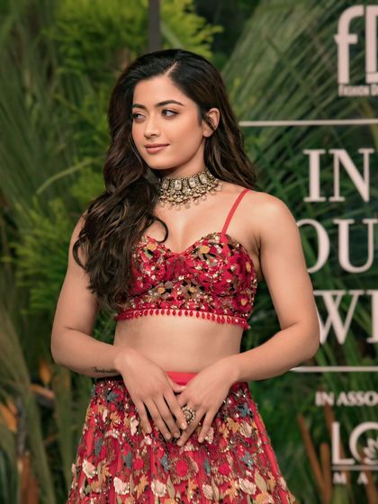National crush Rashmika Mandanna looking radiant in a red embroidered lehenga. A beautiful portrait capturing her grace and charm at a fashion event.