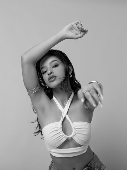 A close-up shot in black and white, focusing on expression and artistry. The hands frame the face, drawing attention to the performance aspect of dance.